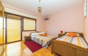 A bedroom with two beds, a red rug, wooden flooring, and a ceiling fan. - Gorgeous apartment in Okrug Gornji (Okrug Gornji)