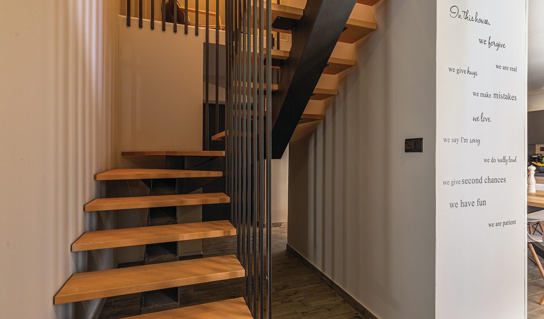 A modern staircase with wooden steps and a metal railing, leading to an upper level.