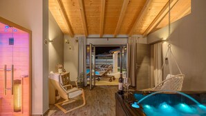 Une salle de spa avec un plafond en bois, un jacuzzi, un fauteuil de relaxation et une vue sur l’espace piscine.