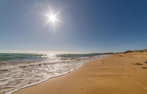 A beach with clear skies and sunlight reflecting off the water.