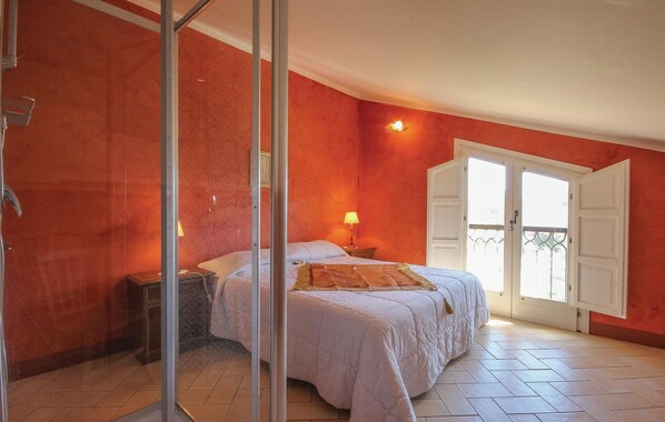 A bedroom with a bed, a nightstand, a lamp, and a sliding glass door to a balcony.