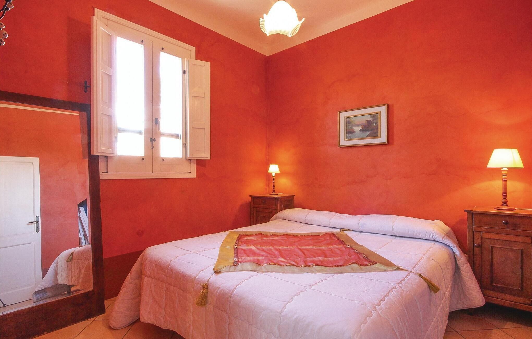 Una camera da letto con un letto, due comodini con lampade, una finestra con persiane e un quadro appeso al muro.