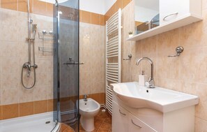 Ein modernes Badezimmer mit Duschkabine aus Glas, einem weißen Waschbecken und einem Bidet.