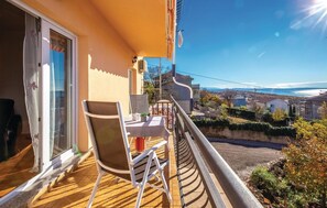 Ein Balkon mit Tisch und Stühlen, der einen Wohnbereich und ein Gewässer blickt.