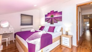 Un dormitorio con cama, mesitas de noche, cómoda y un amplio ventanal.