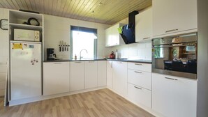 A modern kitchen with white cabinets, a wooden floor, and a built-in oven. - 3 bedroom stunning home in Hjerm (Hjerm)