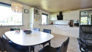A modern kitchen with white cabinets, a dining table with chairs, and a large black leather chair. - 3 bedroom stunning home in Hjerm (Hjerm)