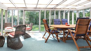 A conservatory with a wooden table and chairs, large windows, and a view of greenery. - 3 bedroom stunning home in Hjerm (Hjerm)