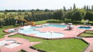 A large outdoor swimming pool with multiple sections and a water slide. - Barrier-free relaxation in a quiet location near the Elbe, the Altmarkt (Sandau/Elbe)
