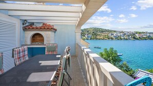 Ein Balkon mit Grill, Tisch und Blick auf einen See und eine Stadt.