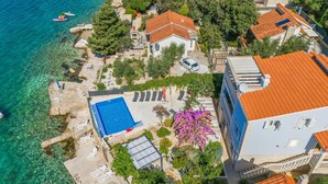Eine Luftaufnahme eines Küsteneigentums mit Swimmingpool, Liegestühlen und einem in der Nähe geparkten Auto.
