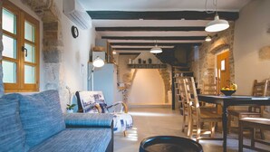 Un salon confortable avec un canapé, un coin repas avec une table et des chaises, et un espace cuisine équipé d’une cuisinière.