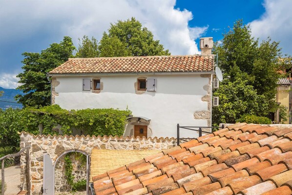 A white building with a tiled roof, a stone wall, and a small door.