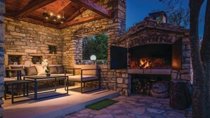 An outdoor patio with stone walls, a fireplace, and outdoor furniture.