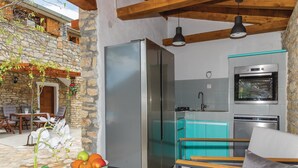 A compact kitchen with a refrigerator, oven, and sink. There is a dining area with a table and chairs.