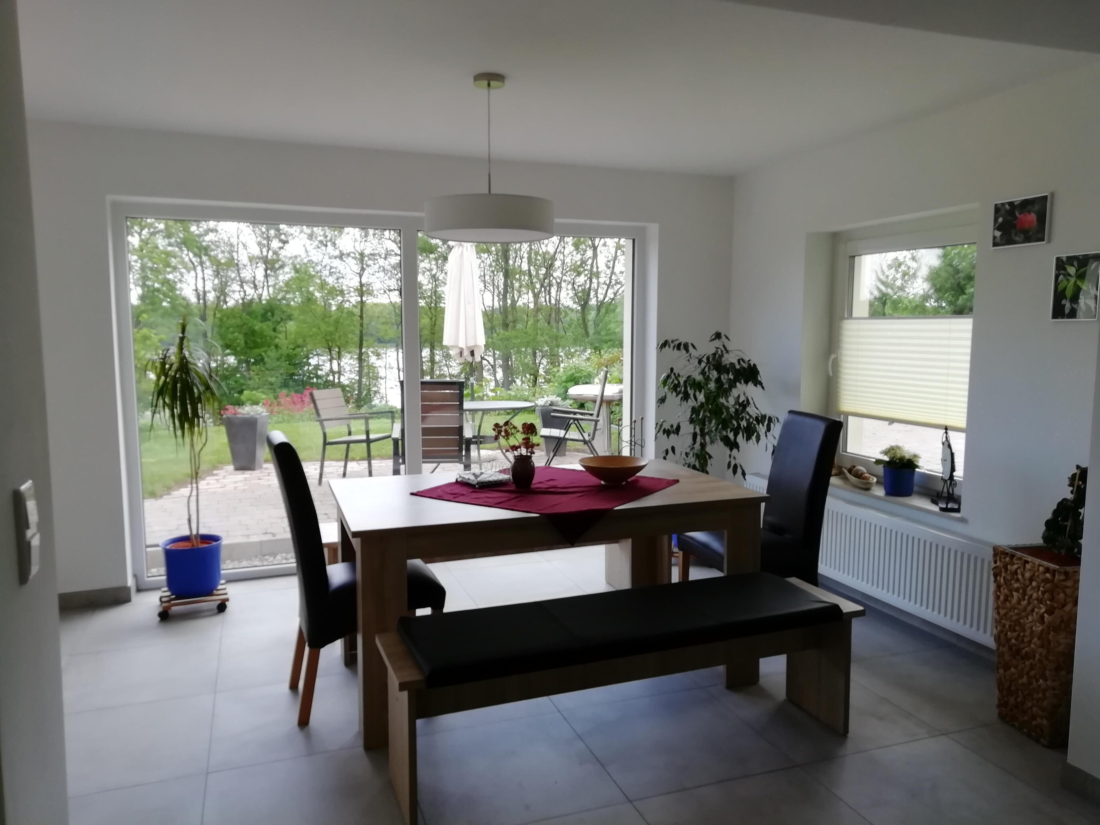 A dining area with a table, chairs, a bench, and a view of the outdoors.
