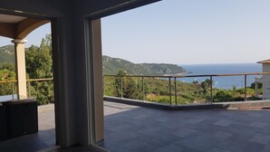 A balcony with a view of the sea and hills.