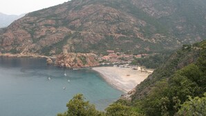 A coastal landscape with a beach, boats, and buildings on a hillside. - Villa with pool, sea view, sleeps 6, tastefully decorated (Lumio)