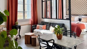 A modern room with a sofa, a dining table, and a bed. - Home Chic Home - Les Suites de La Comédie - Suite2 (Montpellier)