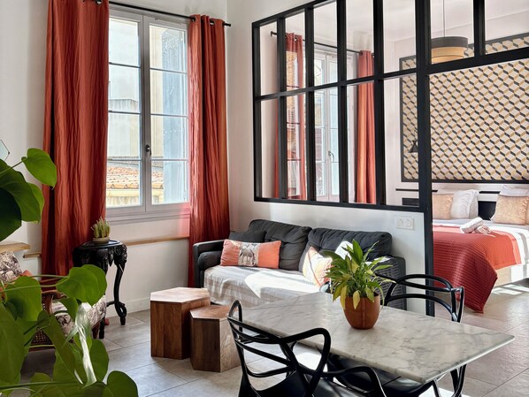 A modern room with a sofa, a dining table, and a bed.