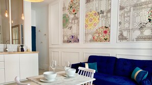 Una cuina moderna amb armaris blancs, un taulell de marbre i un sofà blau amb coixinets verds blaus.