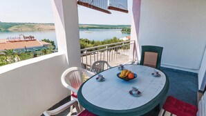 Ein runder Tisch mit Stühlen und einer Obstschale auf einem Balkon mit Blick auf einen See.