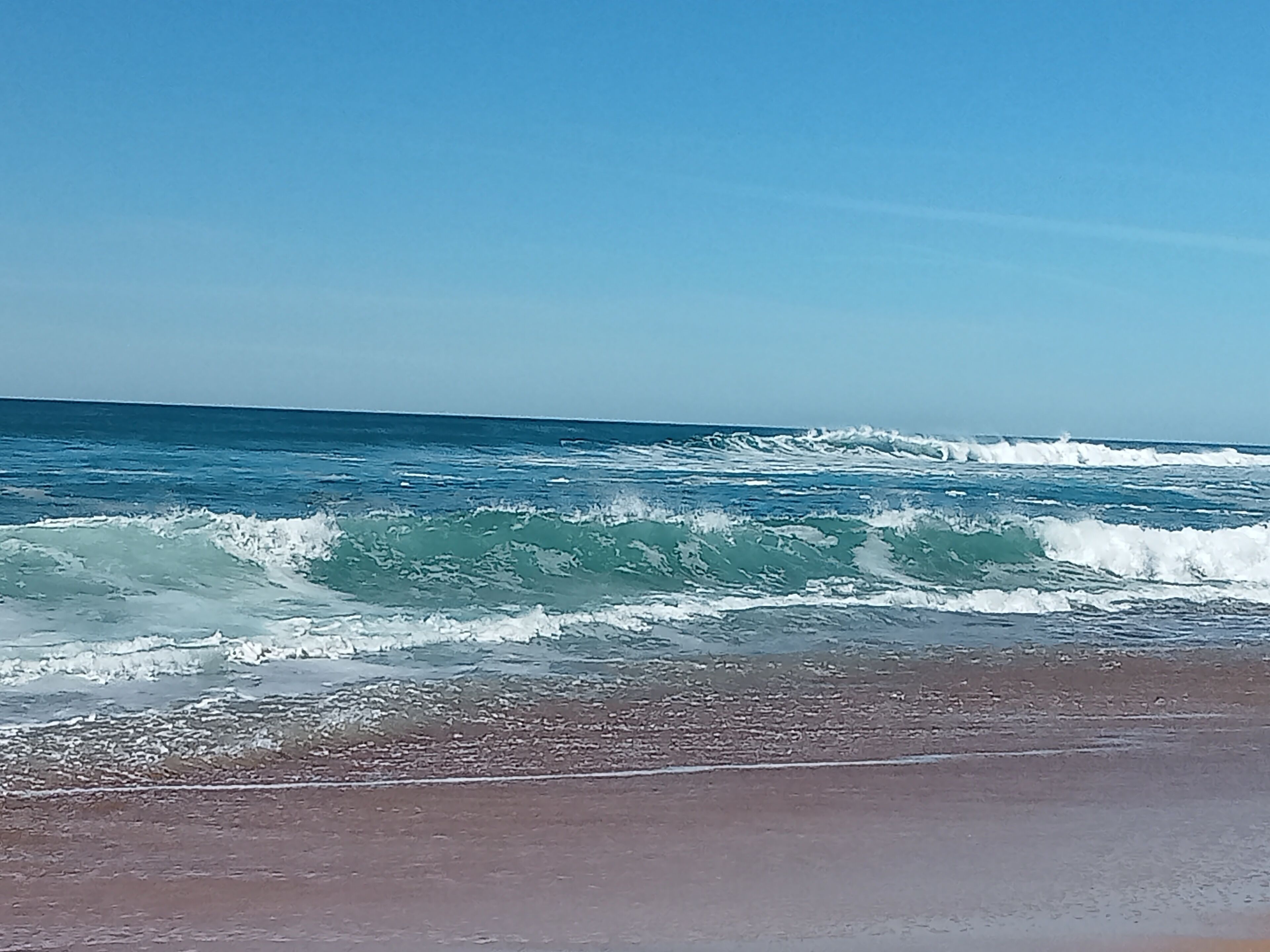Una playa con olas y cielo despejado.