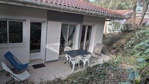 A house with a patio area featuring a table and chairs, a sliding glass door, and a tiled floor. - Garden level apartment, for 5 persons, beach et lake 5 min away, great amenities (Soorts-Hossegor)