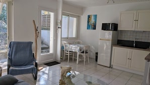 A compact kitchen with white cabinets, a dining table with chairs, a refrigerator, and a microwave. - Garden level apartment, for 5 persons, beach et lake 5 min away, great amenities (Soorts-Hossegor)