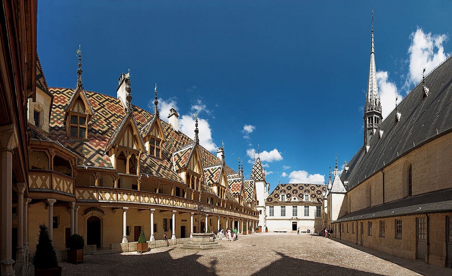 A historic building with a courtyard, featuring ornate facades and a prominent tower.