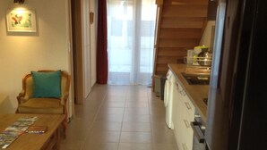 A cozy kitchen with a wooden staircase, a dining area with a table and chairs, and a refrigerator. - Le Gîtele: Cottage 7 people to Chatenois (Châtenois)