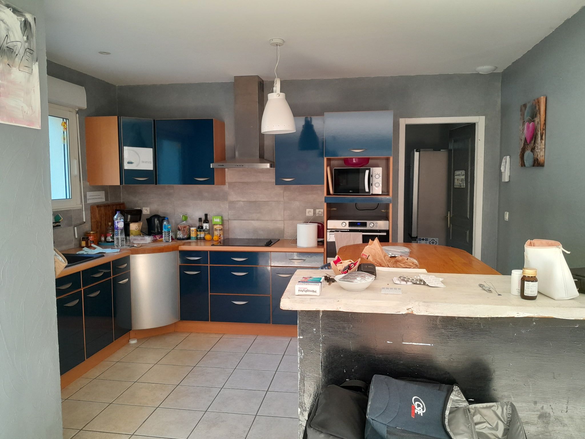 A modern kitchen with blue cabinets, a microwave, and a refrigerator.