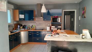 A modern kitchen with blue cabinets, a microwave, and a refrigerator.