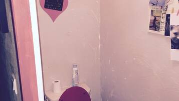 Un bagno con il water rosso, un lavandino bianco e una decorazione a forma di cuore rosa sulla parete.