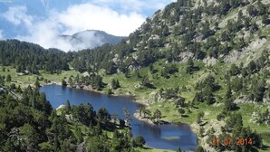 A mountainous landscape with a lake surrounded by dense forests and rocky terrain. - CHALET DES CIMES CHAMROUSSE / 3* TOURIST HOUSE / NEAR THE SLOPES (Chamrousse)