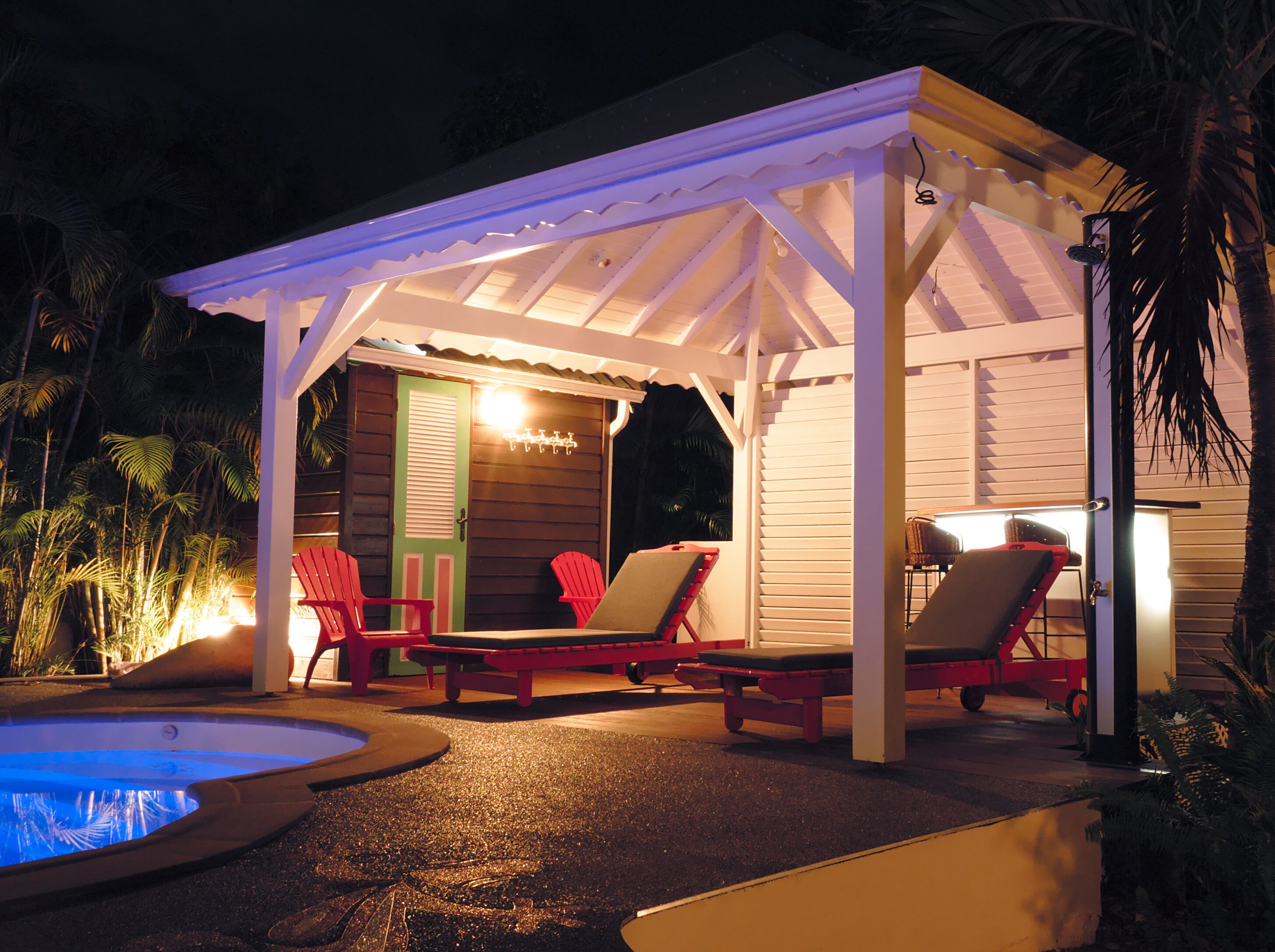 A covered outdoor area with a pool, lounge chairs, and a small table.