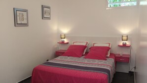 Une chambre à coucher comprenant un lit, deux tables de chevet, deux lampes fixées au mur et deux tableaux encadrés accrochés au mur.