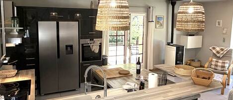 Una cocina moderna con una isla central, electrodomésticos de acero inoxidable y lámparas colgantes de mimbre.