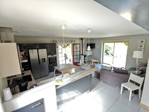 Una cucina moderna con isola centrale, elettrodomestici integrati e zona pranzo con divano e sedie.
