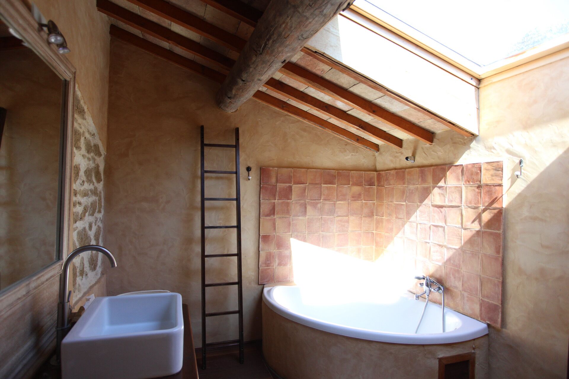 A bathroom with a bathtub, a sink, and a wooden ladder.