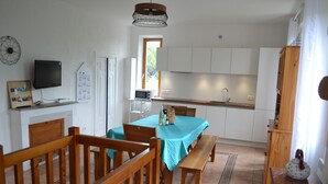 A compact kitchen with white cabinets, a dining table with a blue tablecloth, wooden chairs, and a wooden bench. - TYPICAL VILLAGE HOUSE CORSE  (Levie)