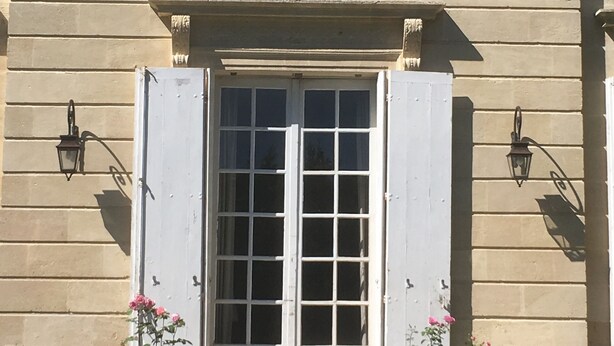 A building with a symmetrical facade, a central entrance with double doors, and two wall-mounted lanterns on either side. - CHARTER OF YESTERYEAR (Sainte-Eulalie)