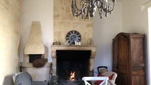 A cozy room with a fireplace, a clock, and a chandelier. - CHARTER OF YESTERYEAR (Sainte-Eulalie)