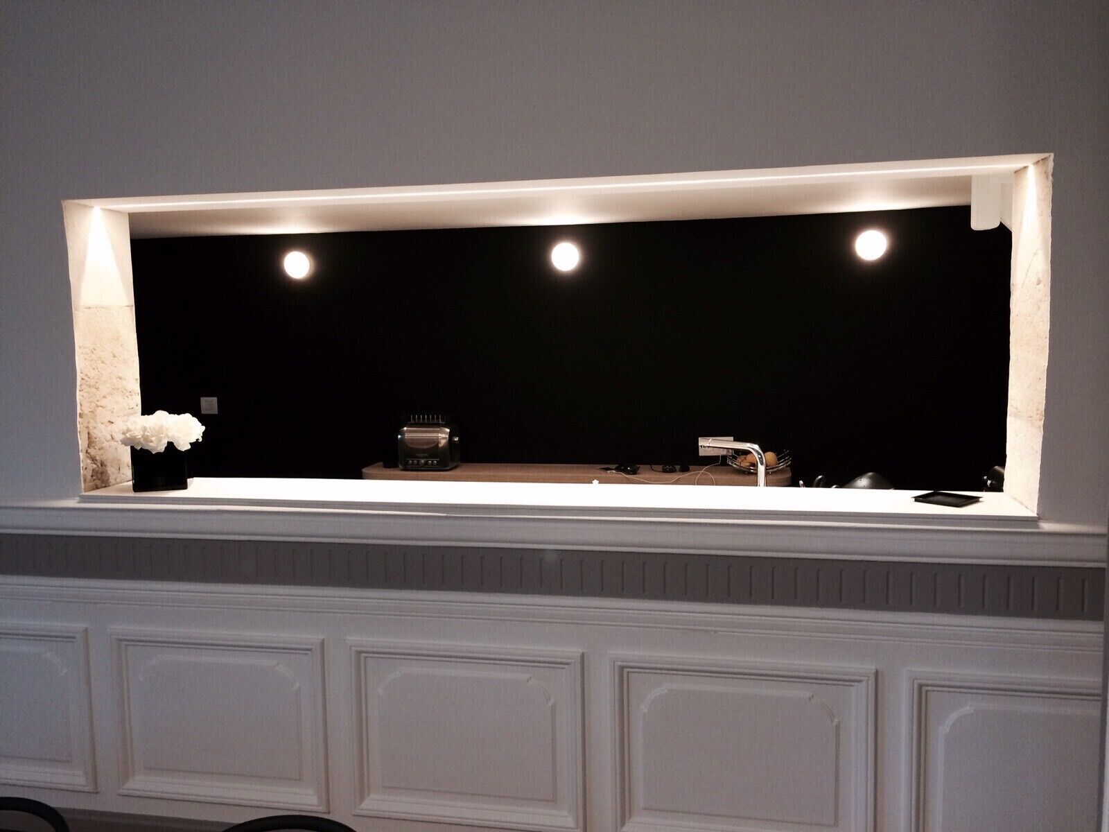 A modern kitchen with a built-in island, under-cabinet lighting, and a dark backsplash.