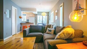 A modern living room with a sofa, a coffee table, and a lamp. There is a kitchen in the background with a window. - Cozy, modern 2BD/2BA townhome minutes from 4 world class ski resorts. (Silverthorne)