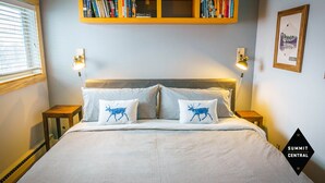 A bedroom with a bed, two pillows with animal prints, bedside lamps, a bookshelf, and a framed map on the wall. - Cozy, modern 2BD/2BA townhome minutes from 4 world class ski resorts. (Silverthorne)