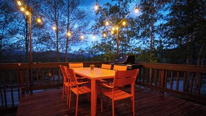 A wooden deck with a table and chairs, string lights, and a grill. - Cozy, modern 2BD/2BA townhome minutes from 4 world class ski resorts. (Silverthorne)