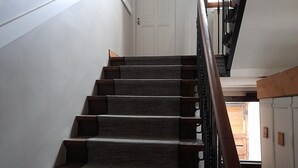 Una escalera con barandilla de madera y peldaños alfombrados que conducen a una puerta.