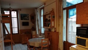 Una cocina compacta con una mesa de comedor, sillas de madera, un refrigerador y un microondas.