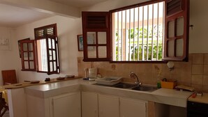 A kitchen with white cabinets, a sink, a coffee maker, and a window with bars. - Nice apartment perfect also for people with reduced mobility (Sainte-Anne)